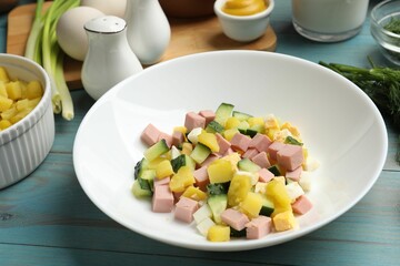 Ingredients for okroshka soup in bowl on light blue wooden table, closeup