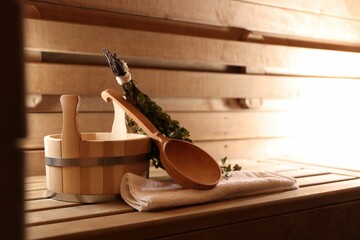 Ladle, towel, bucket and whisk on wooden bench in sauna
