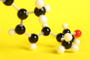 Molecule of retinol (vitamin A) on yellow background, closeup. Chemical model