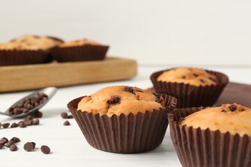 Delicious muffin with chocolate chips on white wooden table, closeup