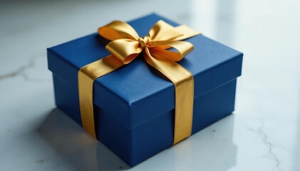Obraz premium Gold ribbon wrapped around a deep blue gift box on a marble surface, luxury item, packaging