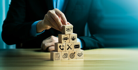 Business customer service concept with a businessman stacking wooden blocks featuring 24/7 support,...