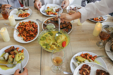 Portrait Of Few Hands Busy Taking Various Food On The Table During Eid Al Fitri Moment