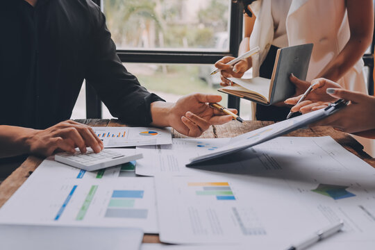 Asian businessman and woman working on laptop with digital tablet and analytical price charts at office desk, Business financial and accounting analytical concept.