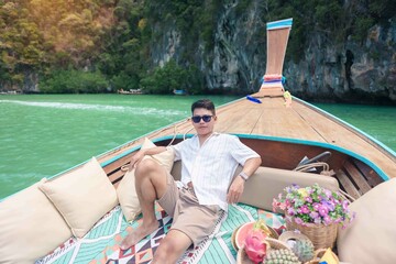 Happy man tourist in private longtail boat trip to koh Hong lagoon island at Krabi, Thailand....