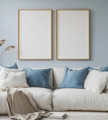 Two empty picture frames hanging above a white couch with blue pillows and a beige throw blanket