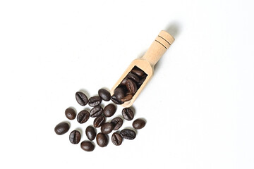 Top view of roasted coffee beans in little wooden scoop with roasted coffee beans around it isolated on white background. Clipping path.