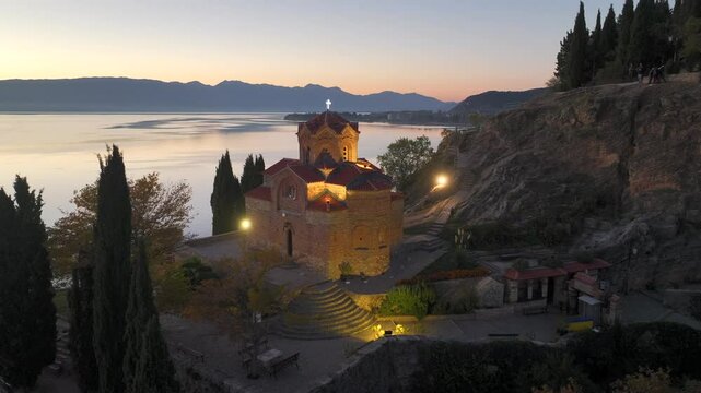 Aerial view of Saint John at Kaneo after sunset. Close-up drone footage of the historic Orthodox church overlooking Lake Ohrid in North Macedonia at dusk.