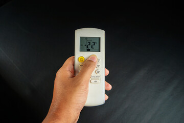 Close up of an Asian man hand with tan skin holding an ac remote