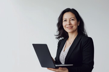 Portrait of a successful middle aged Latina business woman model standing and smiling while holding open laptop. Isolated on gray studio background. Copy space.