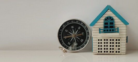 Navigating home a compass and miniature house display indoor still life calm atmosphere close-up exploration theme
