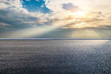 Asphalt road and dramatic sky with sun rays natural background