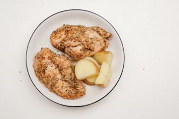 Roasted chicken breast with potato for diet menu on a plate, isolated white background.