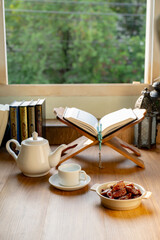 Many Date Palms are on bowls, plates, a cup of water, and the Quran, islamic style lamps on wooden tables, to wait for the time of Iftar, with the concept of ramadan Muslims around the world.