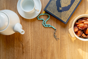 Many Date Palms are on bowls, plates, a cup of water, and the Quran, islamic style lamps on wooden tables, to wait for the time of Iftar, with the concept of ramadan Muslims around the world.