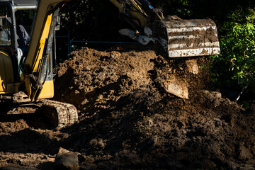 New house construction site earthworks, excavator moving dirt and piling it up, sunny winter day...