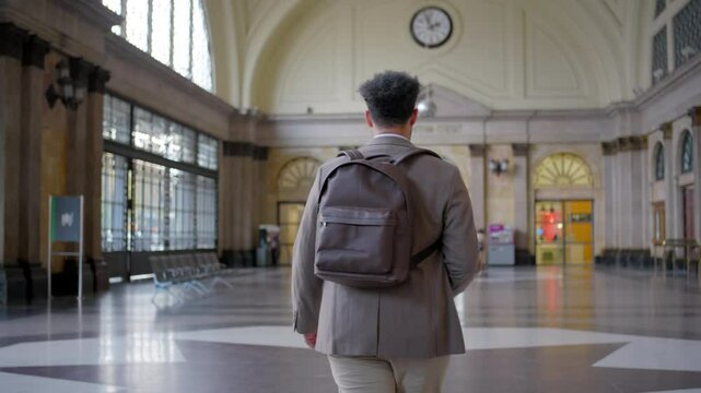 Focused businessman navigates at Barcelona train station lobby, carry his backpack and smartphone efficiently, exuding professionalism as he embarks on another journey filled with opportunities