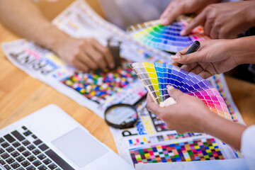 Team graphic designer checking print quality of media graphics proof print and color guides in...