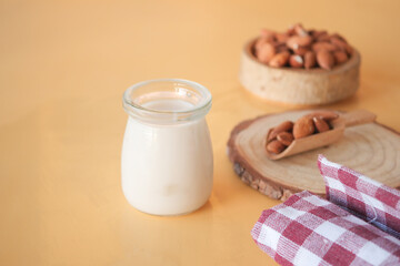 Almond milk in glass jar with nuts on wooden background