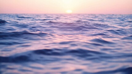 A tranquil view of gentle ocean waves reflecting hues of pink and blue as the sun sets on the horizon, creating a serene and inviting atmosphere.