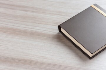 Fototapeta premium close-up photo of elegant leather-bound notebook with gold accents placed on sleek wooden table surface evoking sense
