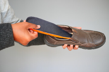 Person placing insoles into a brown shoe for added comfort