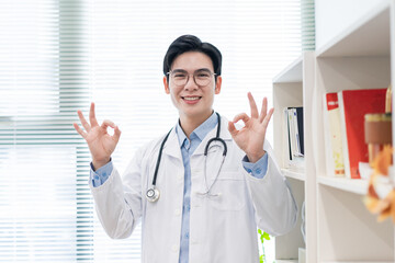 Smiling doctor in a white coat showing positive gestures indoors in a modern healthcare setting