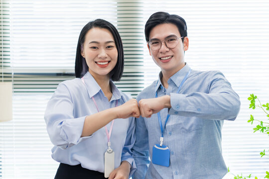 Smiling colleagues share a friendly fist bump while working in a modern office space during the day