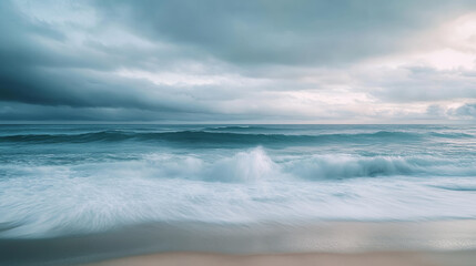 Obraz premium Serene ocean waves crashing on sandy beach under cloudy skies
