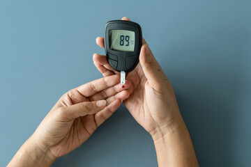 Woman's hands checking diabetes and hyperglycemia with digital blood sugar meter. Healthcare and...