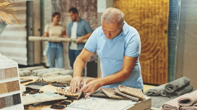 Elderly male shopper looks closely at carpet samples in a hardware store. High quality 4k footage