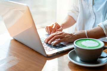Young woman with coffee cup working with laptop in cafe, Digital nomad lifestyle