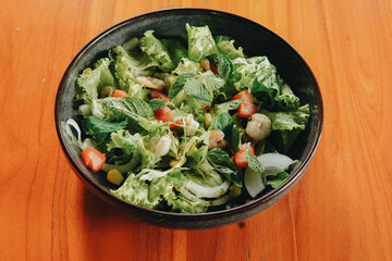 Thai prawn salad with fresh green lettuce and cucumbers, tomatoes and sesame seeds.