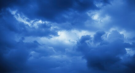 Obraz premium dark stormy sky, ominous clouds, deep blue hues, dramatic lighting, moody atmosphere, ethereal cloudscape, turbulent weather, foreboding sky, celestial landscape, high contrast, textured clouds, atmos