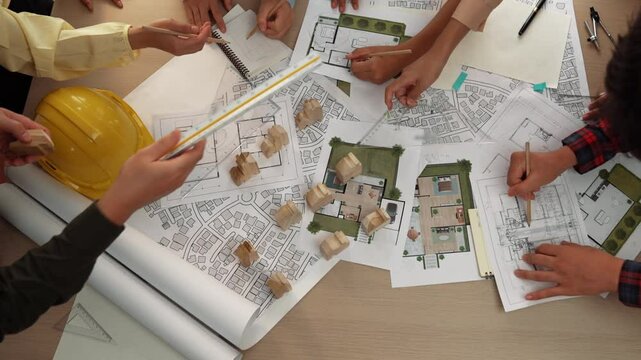 Architect and safety engineer discussion about building construction use blueprint on table with architectural document, measurement tool and wooden block scatter around at modern office. Delineation.