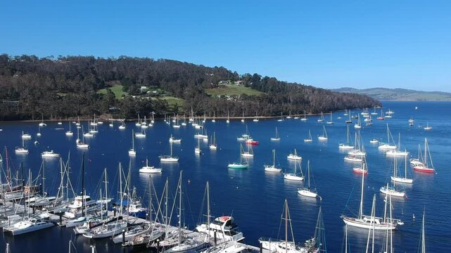 Aerial drone footage of Oyster Cove Marina and Little Kettering Marina, Bruny Island, Tasmania, showcasing boats, calm waters, scenic coastline, lush surroundings, and a tranquil harbor
