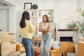 Asian girl friends enjoy dancing during packing stuff into the cardboard box for moving house. People excited for chance and new beginning of life.