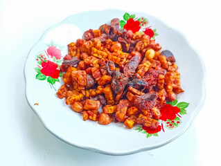 Delicious Indonesian dish of fried tempeh, liver and peanuts on a decorative plate, close up