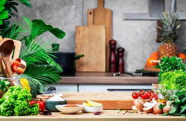 Cooking with love: rustic kitchen full of flavor and life, food background. Empty oak cutting board with mushrooms, tomatoes, lettuce, broccoli on cozy kitchen with wooden table, kitchenware 