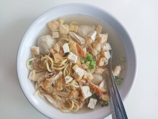 Delicious Indonesian Soto Ayam Soup with Noodles, Chicken, and Tofu in a White Bowl