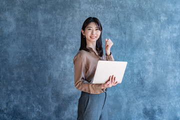 パソコンを持ちガッツポーズをする女性
