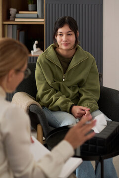 Vertical portrait of teenage girl listening to therapist in meeting and of troubled teenage girl sharing mental health problems