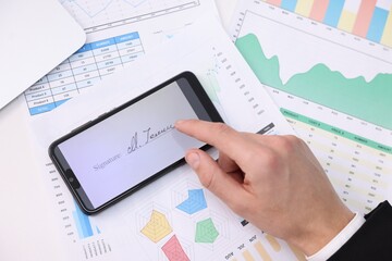 Electronic signature. Man using smartphone at table, top view
