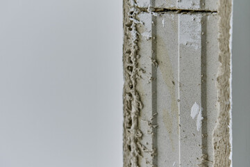 Close-up of unfinished doorway with unfinished concrete wall corner with rough plaster. Construction works and house renovation concept