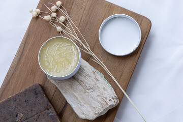 A sophisticated spa-inspired composition featuring a balm placed on a natural stone, set against the smooth drape of white satin for a calming effect.
