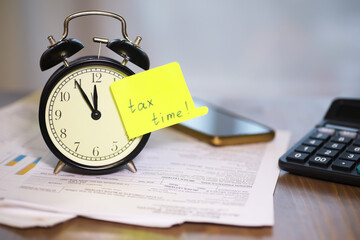 Alarm Clock with Tax Time Note on Financial Documents, Calculator, and Smartphone