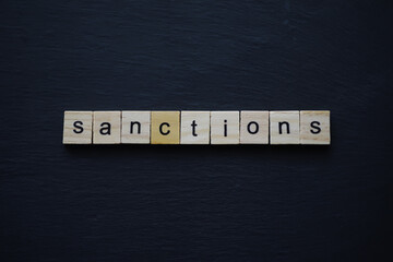 Sanctions Concept Depicted with Wooden Letter Tiles on Dark Surface