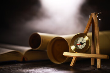 Vintage Brass Compass on Wooden Tripod with Old Maps and Books on Wooden Table, Concept of Exploration and Adventure