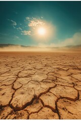 Barren desert landscape with cracked ground and sunlight rays against a blue sky