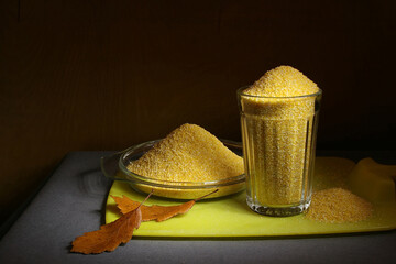 Corn grits in a glass bowl stand on a yellow cutting board